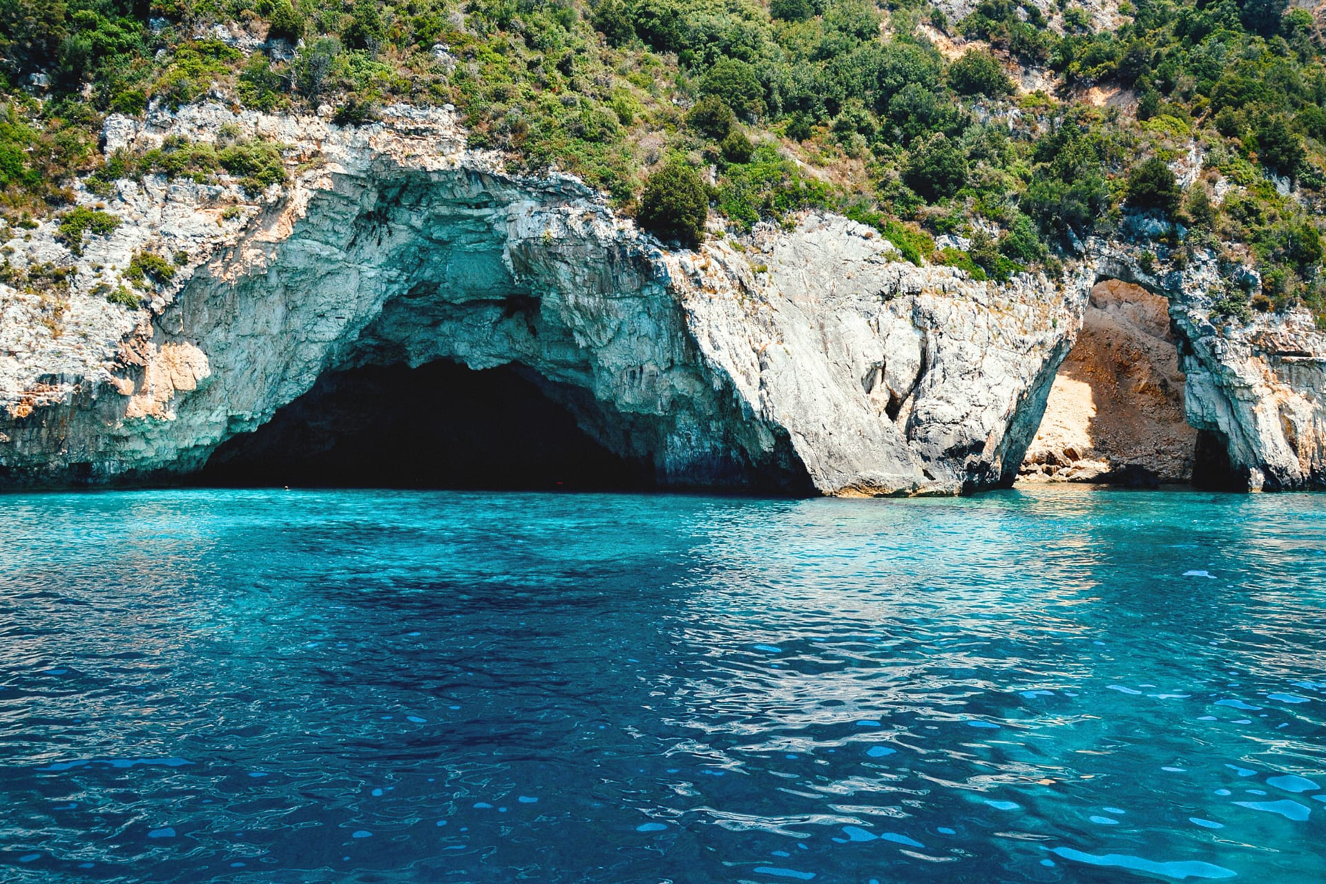 The Blue Caves in Paxos, Greece - famous sea caves in the Ionian Sea with stunning clear blue water for swimming and boat tours