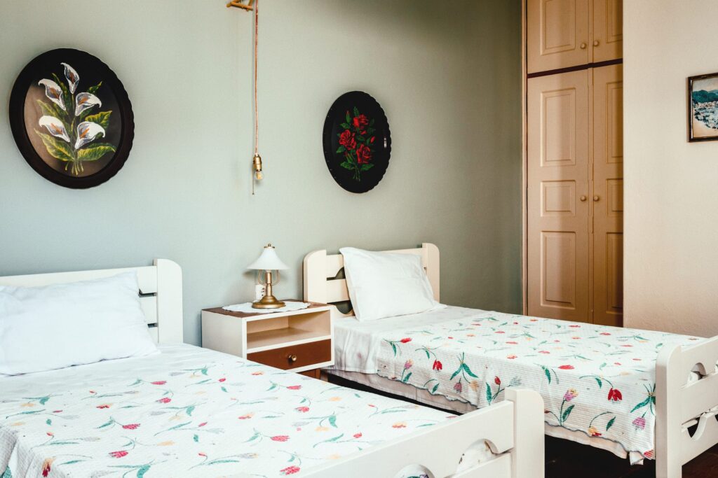 Cozy ground-floor studio bedroom in Paxos with embroidered wall art, rustic beds, and warm lighting